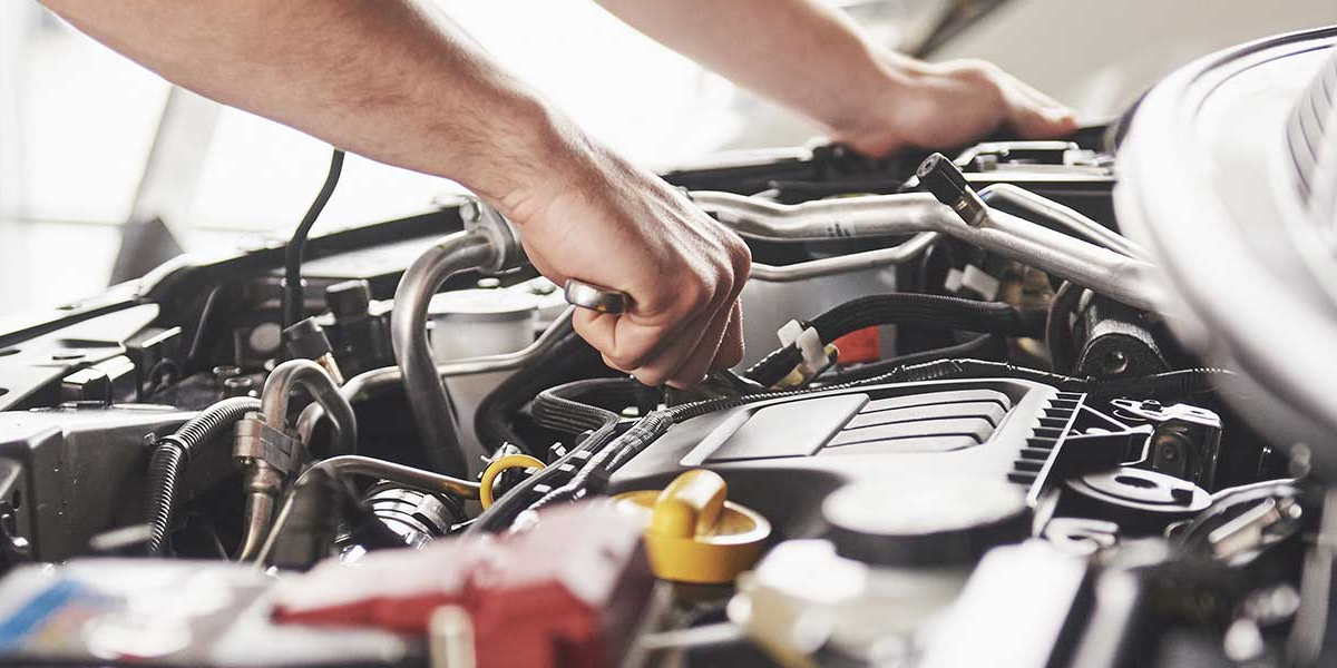 A technician working underneath the hood of a vehicle
