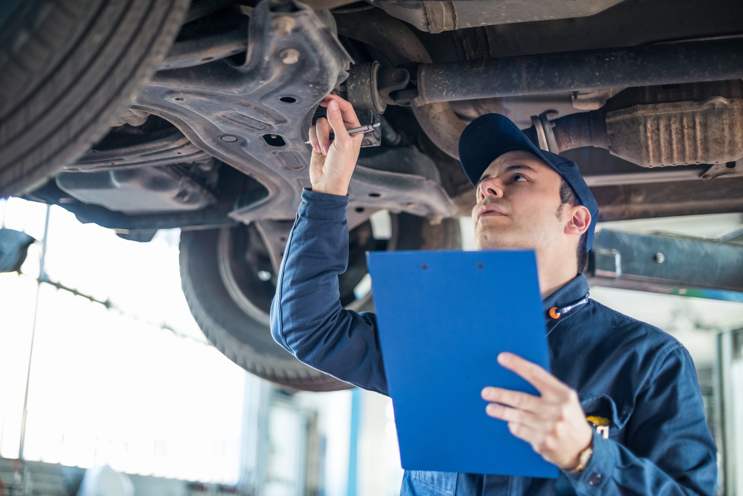 A mechanic inspecting the underside of a car
