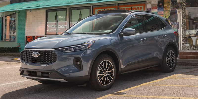 Gray Ford SUV parked in front of a storefront on a city street.