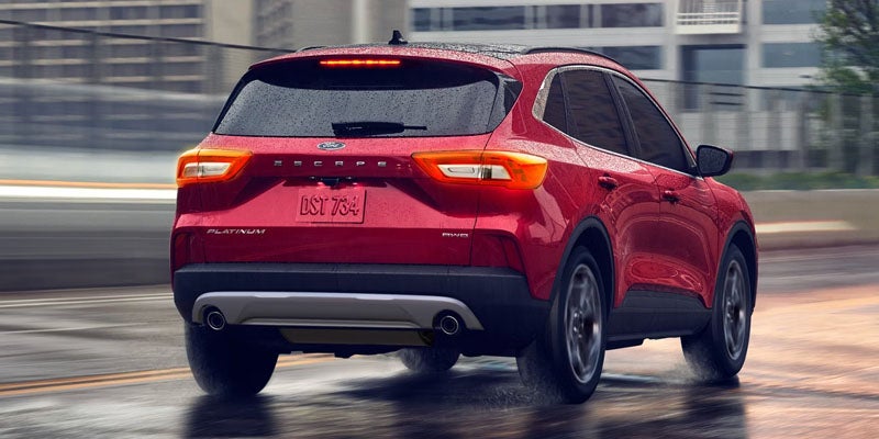Red 2026 Ford Escape SUV driving on a wet city road.
