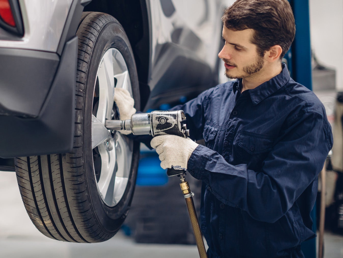 Mechanic using an impact wrench to service a car wheel.